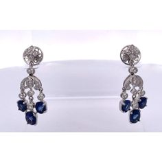 This is part of Chairish’s Fine Jewelry assortment.  Sapphire Tassel Diamond Drop Earrings 18K  Just received from a London auction, these tassel drop earrings are divine. These Sapphire tassel earrings have extra beautiful clean clear deep Blue Sapphires and are made in 18K White Gold. These Sapphire Tassel Drop Earrings features a fleur de lis top is studded with Diamonds and suspending from them are 3 oval Sapphires. Two Sapphires are approximately 0.30 points each and the center Sapphire is Luxury Pierced Chandelier Earrings For Formal Events, Classic Chandelier Dangle Earrings With 17 Jewels, Fine Jewelry Briolette Earrings For Evening, Luxury White Gold Long Drop Earrings, Luxury Long Drop Earrings For Formal Occasions, Fine Jewelry Chandelier Earrings With 17 Jewels, Fine Jewelry Chandelier Drop Earrings, Exquisite Dangle Earrings For Formal Occasions, Luxury Pierced Dangle Chandelier Earrings