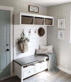 a white bench with baskets on it in front of a door and some pictures hanging on the wall