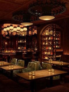 a dimly lit bar with candles on the tables and chairs in front of shelves filled with liquor bottles