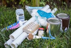 an assortment of toiletries sitting in the grass next to cans and toothbrushes