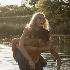 a woman is being hugged by a man in the water while he stands on his knees