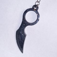 a black metal object on a chain that is hanging from it's side with a hole in the middle