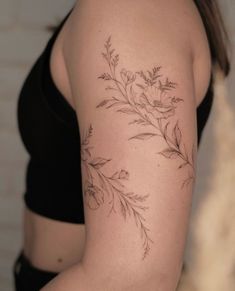 a woman with a tattoo on her arm that has flowers and leaves drawn on it