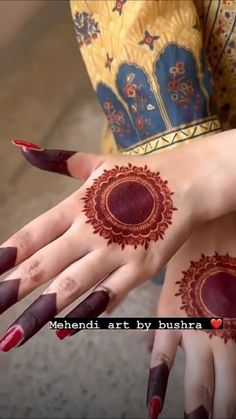 two women's hands with hendi designs on their palms and fingers, both painted red