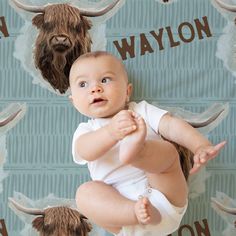 a baby sitting in front of a wall with long horns on it's head