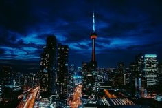 the city skyline is lit up at night with bright lights and skyscrapers in the background