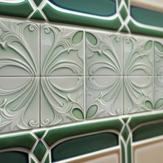 a close up view of some decorative tiles on the side of a building with green and white designs