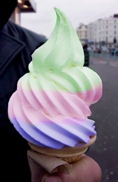 a person is holding an ice cream cone with white icing on it's tip