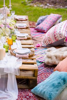 a table set up with plates, glasses and napkins on top of an area rug