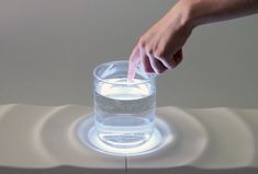 a person's hand reaching into a glass filled with water