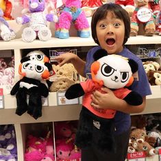 a young boy holding two stuffed animals in front of shelves with teddy bears on them