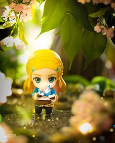 a little figurine sitting on top of a table in front of some flowers