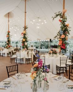 an indoor tent with tables, chairs and flowers in vases on the table top