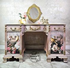 an ornate pink desk with flowers and birds painted on the drawers is shown in front of a gold framed mirror