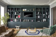 a living room filled with furniture and a flat screen tv mounted on a wall next to a window