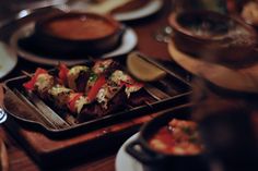 there are many different types of food on the trays at this dinner table, including skewers of meat and vegetables