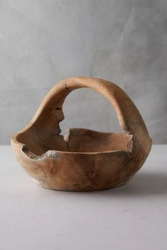 a wooden bowl sitting on top of a white table next to a gray wall and floor