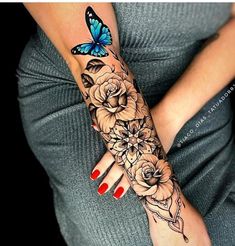 a woman's arm with flowers and a butterfly tattoo on her left hand,