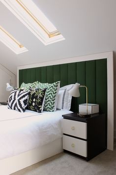 a bedroom with green headboard and white bedding