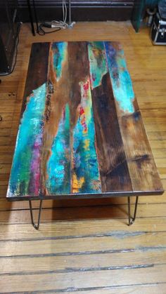 a coffee table made out of wood and metal legs with colorful paint on the top