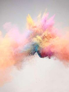 colorful powder is flying in the air on a gray and white background as if it were an explosion