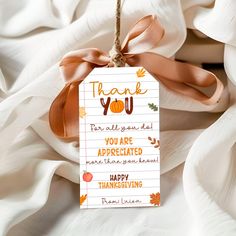 a thank you tag hanging from a string on a white sheet with leaves and pumpkins