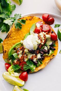 a taco with black beans, tomatoes, lettuce and sour cream on top