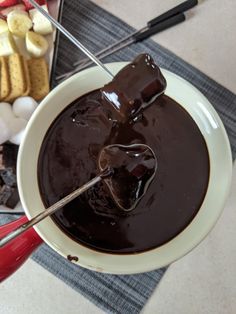 a bowl filled with chocolate and marshmallows on top of a table next to other foods