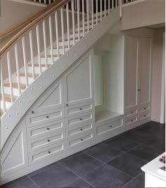 an empty room with white cabinets under the stair case and stairs above it are also built into the wall