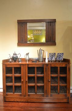 a wooden cabinet sitting on top of a hard wood floor next to a wall mounted mirror