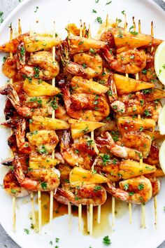 grilled shrimp and pineapple skewers on a white plate with lemon wedges