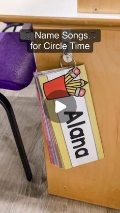 the name song for circle time sits on top of a wooden desk with purple chairs