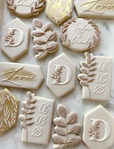 some cookies are decorated with gold and white icing on a marble slabd surface