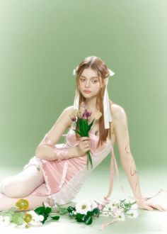 a woman in pink dress sitting on the ground with flowers