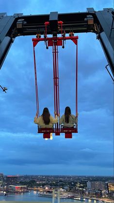 two people are sitting on a ferris wheel at night, with the city in the background