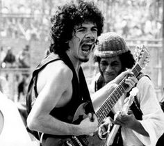 a man with his mouth open playing an electric guitar in front of a large crowd