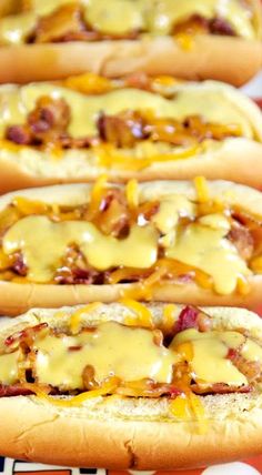 four hotdogs with cheese and onions on a red tray in front of polka dot tablecloth