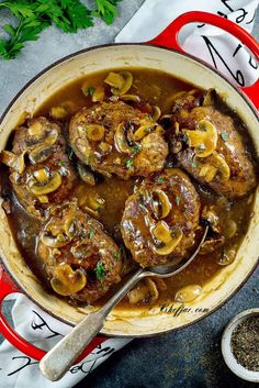 a red pot filled with meat and mushrooms