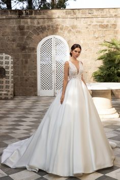 a woman in a white wedding dress standing on a checkered floor with an archway behind her