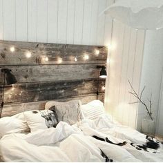 an unmade bed with white sheets and lights on the headboard is pictured in this image