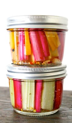 three jars filled with pickled vegetables sitting on top of a table