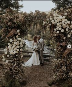 a bride and groom standing under an arch with flowers