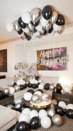 black and white balloons are hanging from the ceiling above a couch in a living room