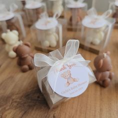 small clear boxes with teddy bears in them on a wooden table, one has a white bow and the other has a label that says thank you