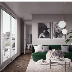 a living room with green couches and pictures on the wall above them, along with a coffee table