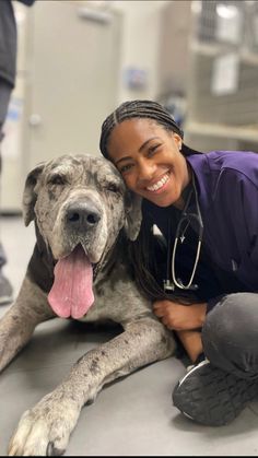 a woman is hugging her dog on the floor in an animal hospital with other people nearby