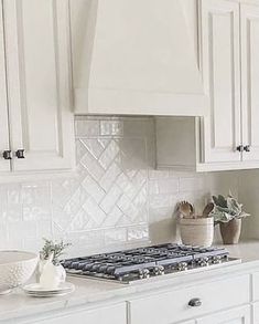 a kitchen with white cabinets and an oven in the center, surrounded by potted plants