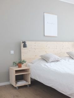 a bed with white sheets and pillows on top of it next to a wooden night stand