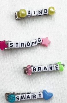 three charms with words on them that say strong, strong, brave, smart and smart