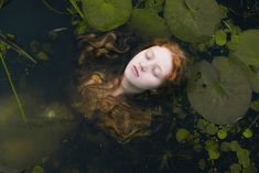 a woman is floating in the water with her eyes closed